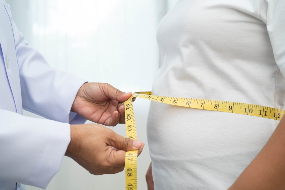 Doctor measuring a patient's waist with a tape measure during a supervised semaglutide vs tirzepatide medical weight loss consultation