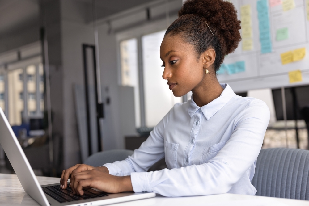 Woman concentrating while working on a laptop in an office setting representing improved focus and mental clarity after addressing BHRT and brain fog through hormone therapy
