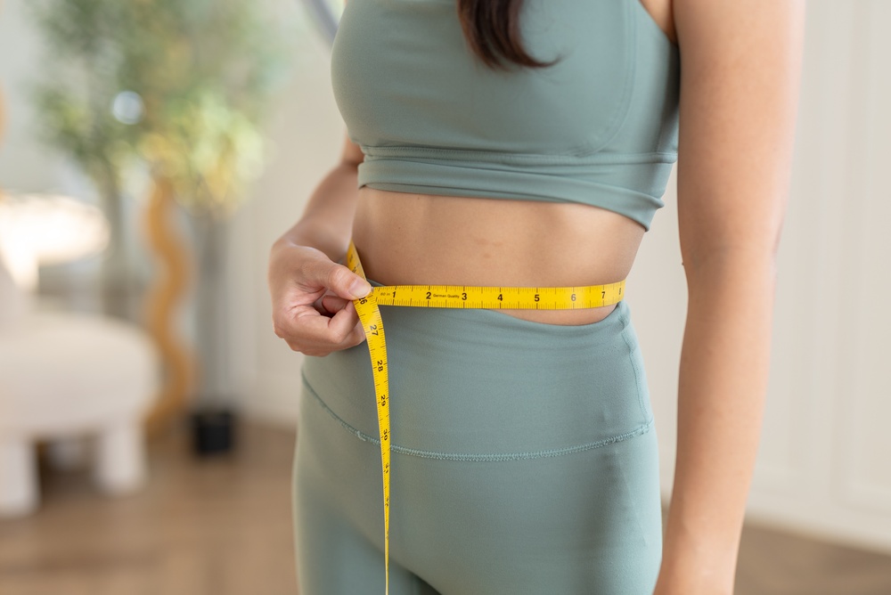 Woman measuring her waist showing progress from a medical weight loss clinic serving Cherry Hill NJ