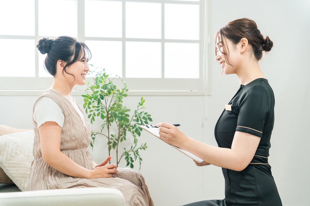 Female patient smiling during a provider consultation with a clipboard representing a structured BHRT follow-up schedule and the importance of regular monitoring during bioidentical hormone therapy