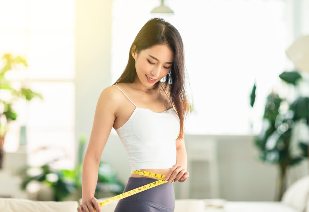 Woman measuring her waist showing progress from a medical weight loss clinic serving Haddonfield NJ