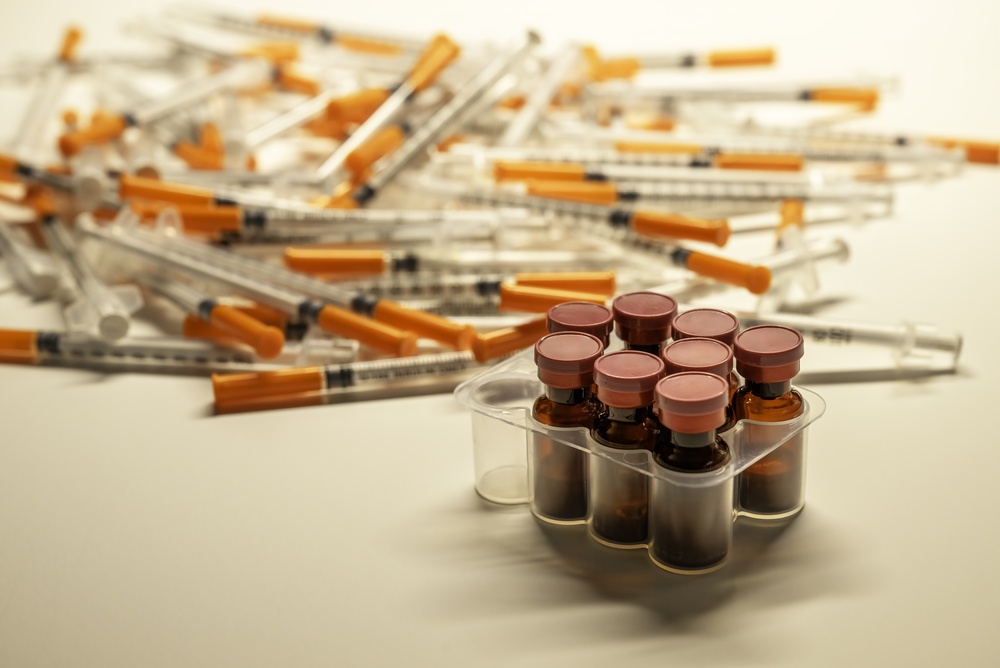 Amber glass medication vials in a clinical tray alongside syringes representing the injectable compounds associated with the most common types of peptides used in therapy