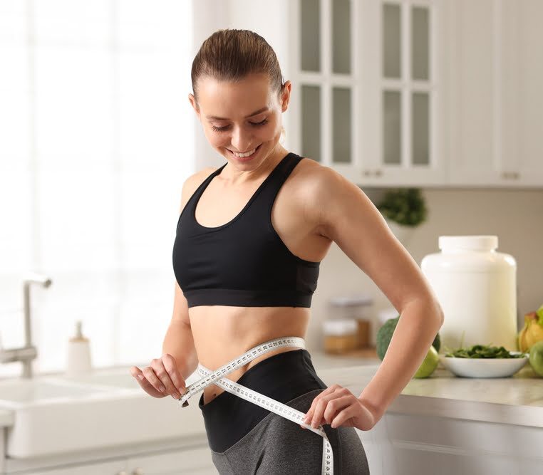 Woman measuring her waist showing progress from a medical weight loss clinic serving Mount Laurel NJ
